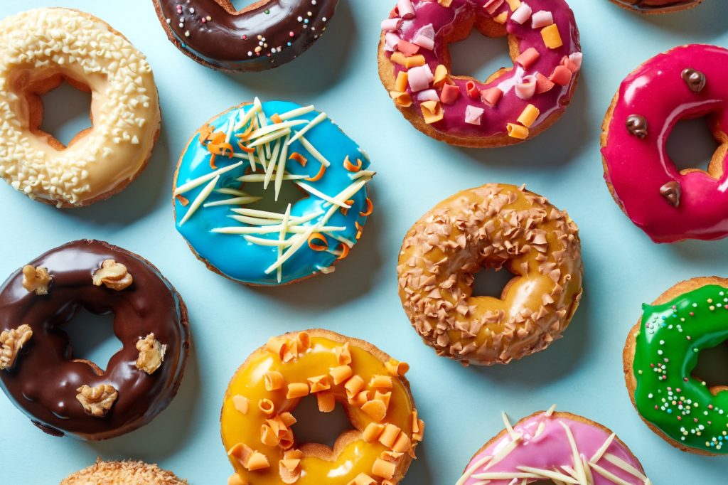 Various donuts on blue background, from above to represent Hiring a marketing agency