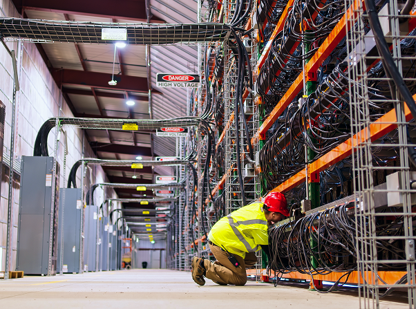 Man in a hard hat and hi-vis vest kneeled down managing cables